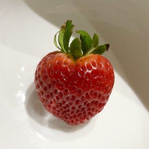 A photo of a single red strawberry on a white background.