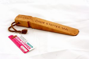 A wooden door stopper with a product tag.