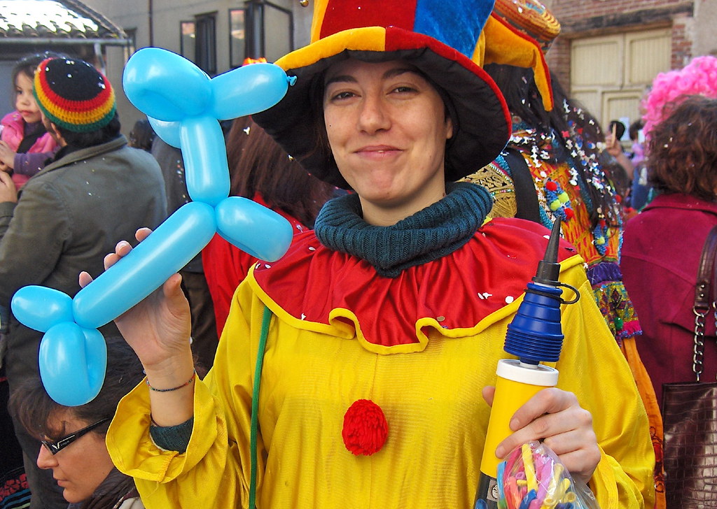 A children's entertainer holds up a balloon animal dog and an air pump