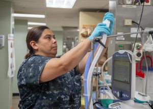 A health care worker adjusts a tube for a ventilator.