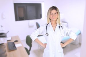 A woman wearing a lab coat and a stethoscope poses with her hands on her hips.