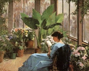 A woman reading in a plant conservatory seen from behind. Flowers in terracotta pots to the woman’s left and right, and a large green plant with overhanging leaves in the background. Large glass windows on the right and across the background; outside the windows is a blurry landscape.