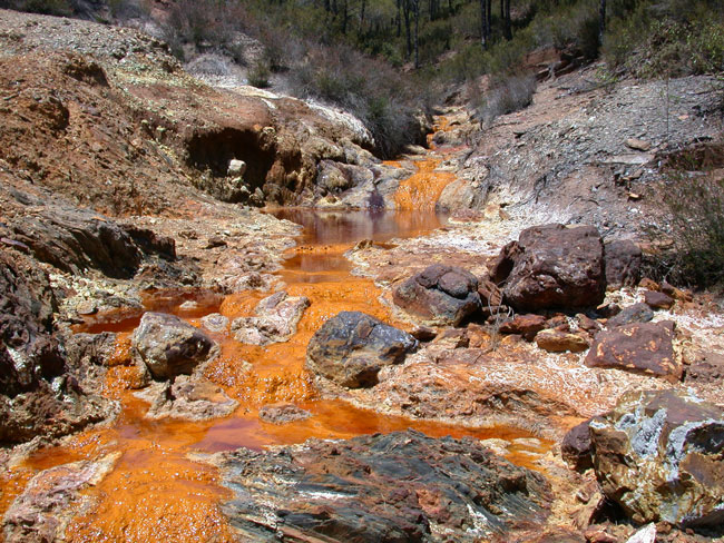 Photograph of rusty-looking Rio Tinto in Spain. This appearance is a result of acid mine tailings. The red colour is from oxidized, precipitated iron (i.e. rust).