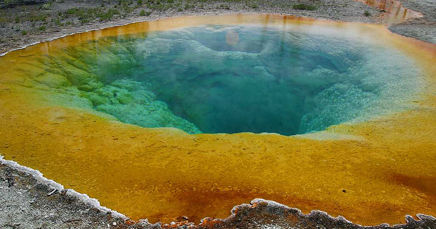 A photograph of a hot spring. The orange colour at the edges, and the bright blue centre are due to the microbes that are growing in the various water temperatures..