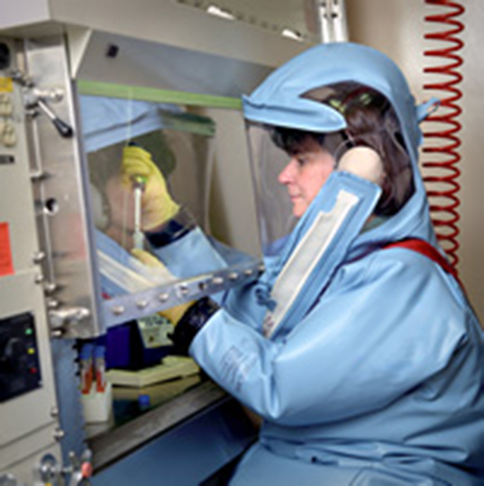 A photo of a lab worker in a suit that completely covers them (including their face and hands).