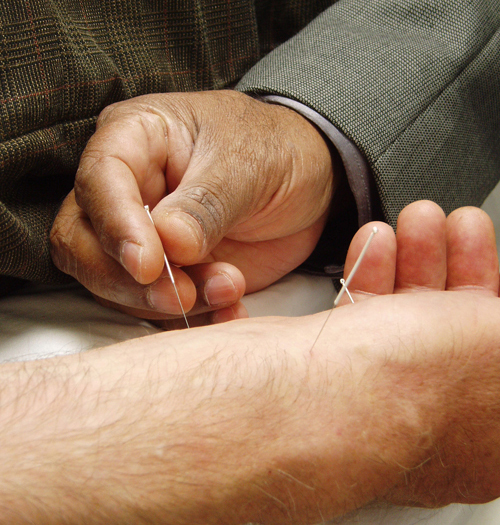 Picture of a person putting a thin needle into another person’s arm.