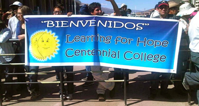 People holding a banner that reads "Bienvenidos; Learning for Hope; Centennial College"