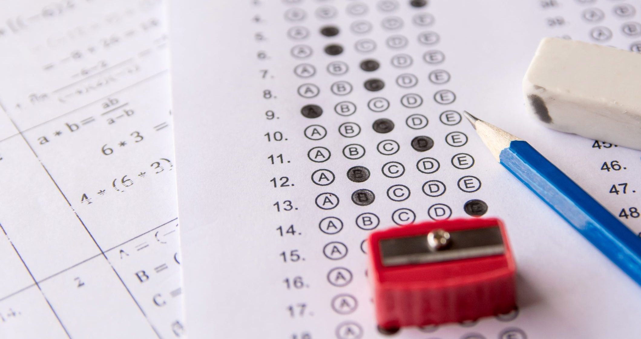 Pencil, Sharpener and eraser on answer sheets or Standardized test form with answers bubbled. multiple choice answer sheet