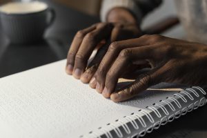 Hands reading braille notebook