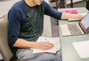 student reading notes on his lap during an exam