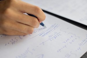person solving equations on paper