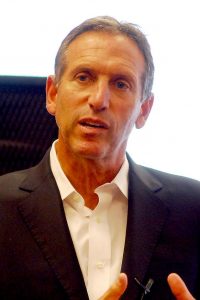 Headshot of a man in his 50-60s wearing a black blazer and a white shirt