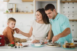 Une mère et un père dans la cuisine avec leur fils qui est sur le comptoir