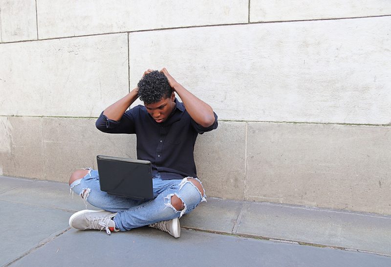 Man with laptop looking frustrated.