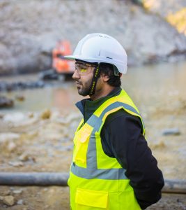 Man wearing safety suit standing outdoors.