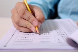 Selective focus of a hand with a pencil writing on a test paper.