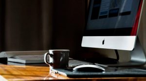 View of desk with computer, books and cup.