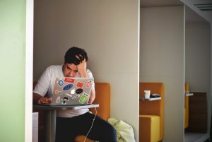 Man wearing white top using MacBook.