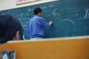 Man at blackboard writing a math calculation.