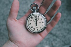 Person holding white and silver-colored pocket watch.