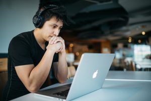 Student with headphones sitting at a table with a laptop.