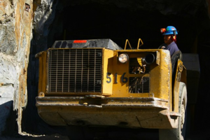 A man in a hardhat navigating a large piece of machinery.