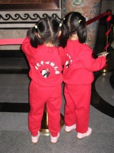 A photograph of twin girls wearing matching red outfits.