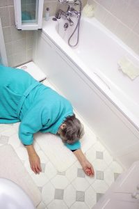 An elderly woman lying injured on a bathroom floor after a fall.