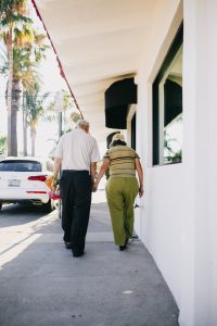 Elderly couple walking while holding hands.