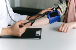 A doctor measuring a patient's blood pressure with a blood pressure arm cuff.