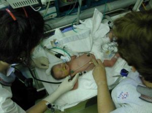 A photograph of a newborn being treated by a medical team.