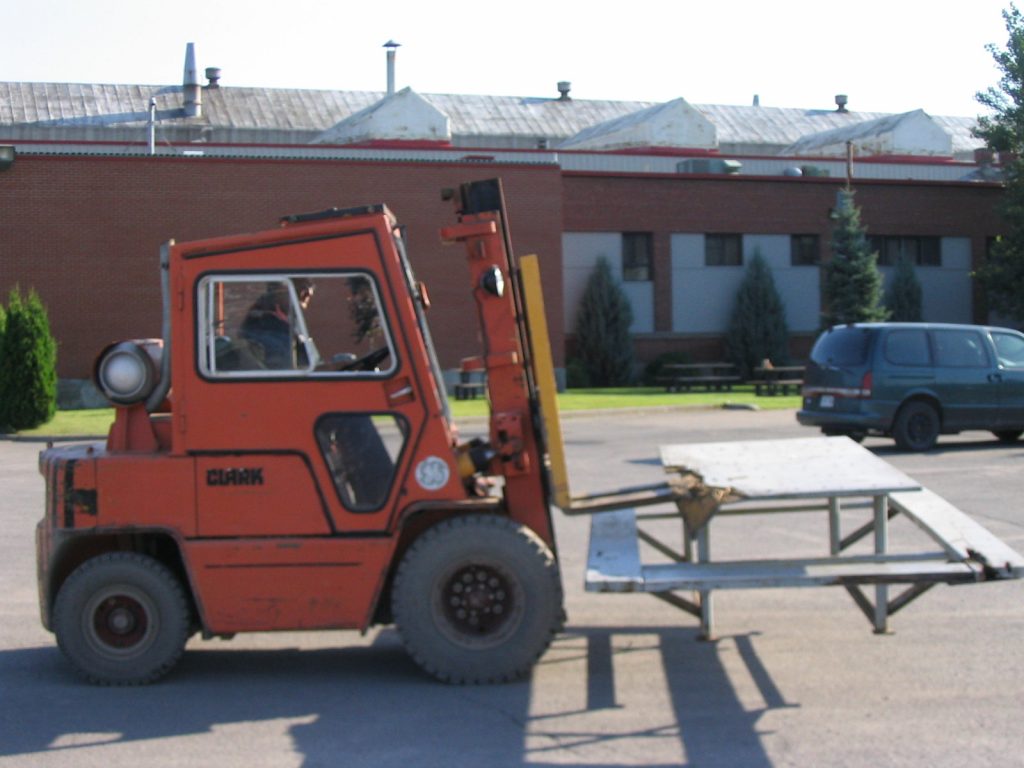 Forklift moving a picnic table