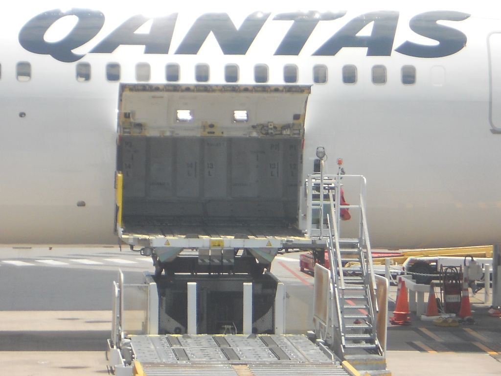 Open cargo hold of a Qantas jet with steps to the side.