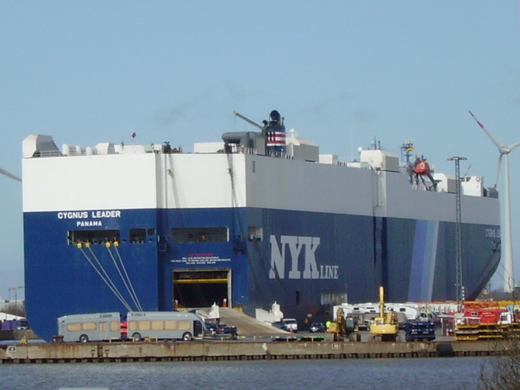 A large blue and white cargo ship which transports vehicles.