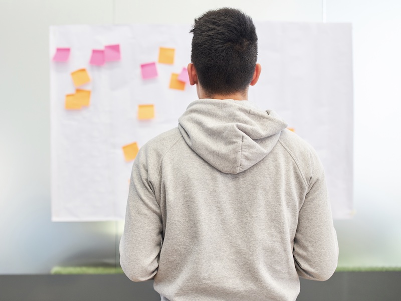 Man standing in front of an ideas board with sticky notes