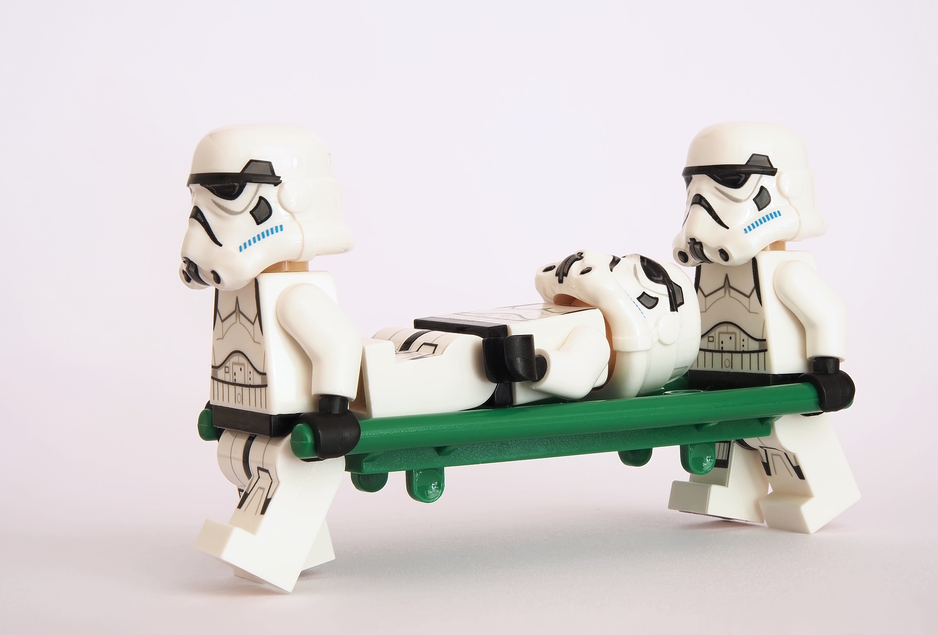 Two Star Wars LEGO characters (storm troopers) carrying a third character on a hospital stretcher