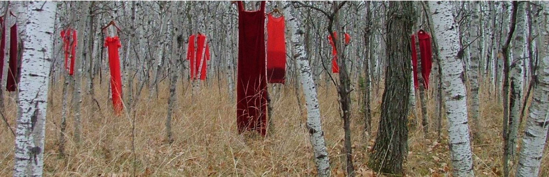 An art exhibition showing red dresses hanging from trees