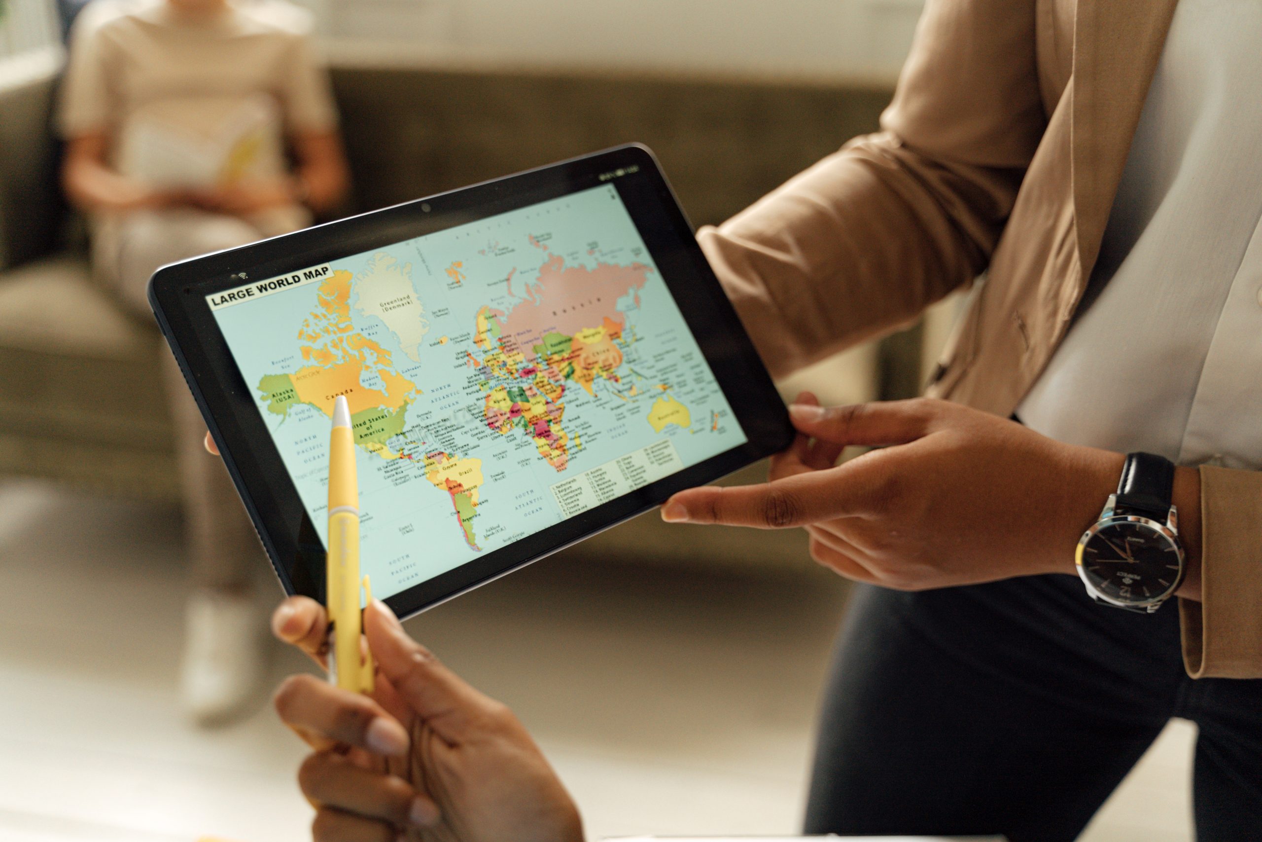 Close-Up Photo of a Person Holding a Tablet Computer Showing the World Map