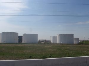 oil storage facility with blue sky and grass in the foreground
