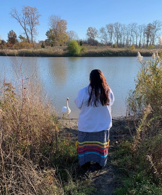 Jaimie Kechego est photographiée, au bord d'un lac local, avec un cygne qui cherche à interagir avec elle.