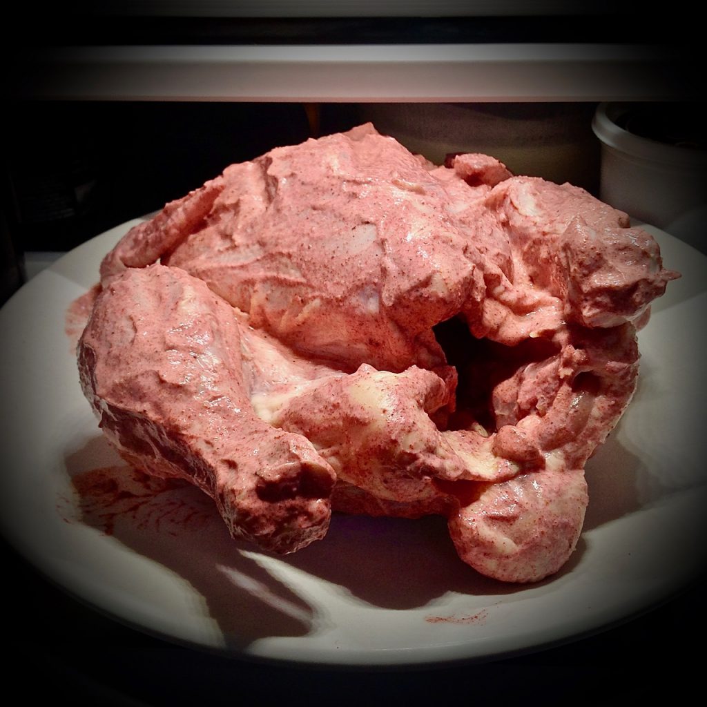 a vignette of a raw chicken covered in pink paste
