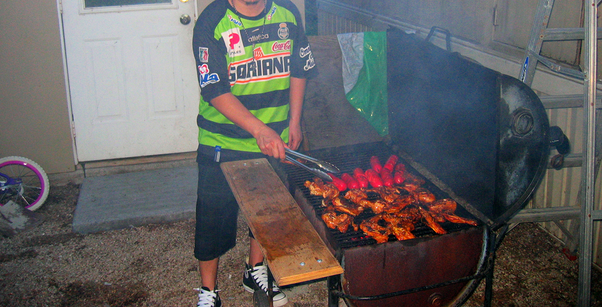 a person tending an outdoor grill with food on it
