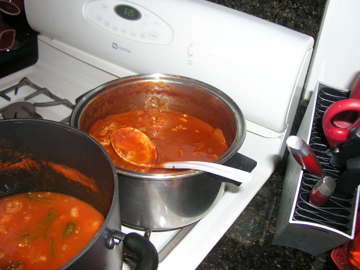 two pots on a stove top with red soup in them