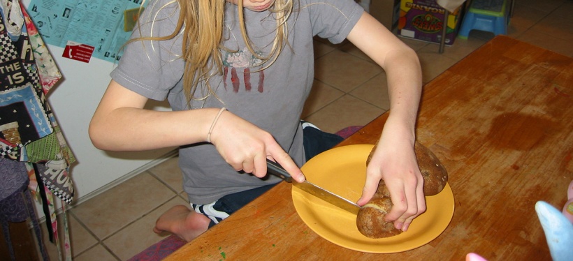 a young person slicing a potato on a plate