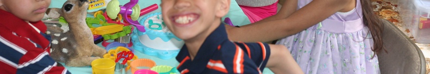 smile on the face of a boy with a table full of brightly colored toys