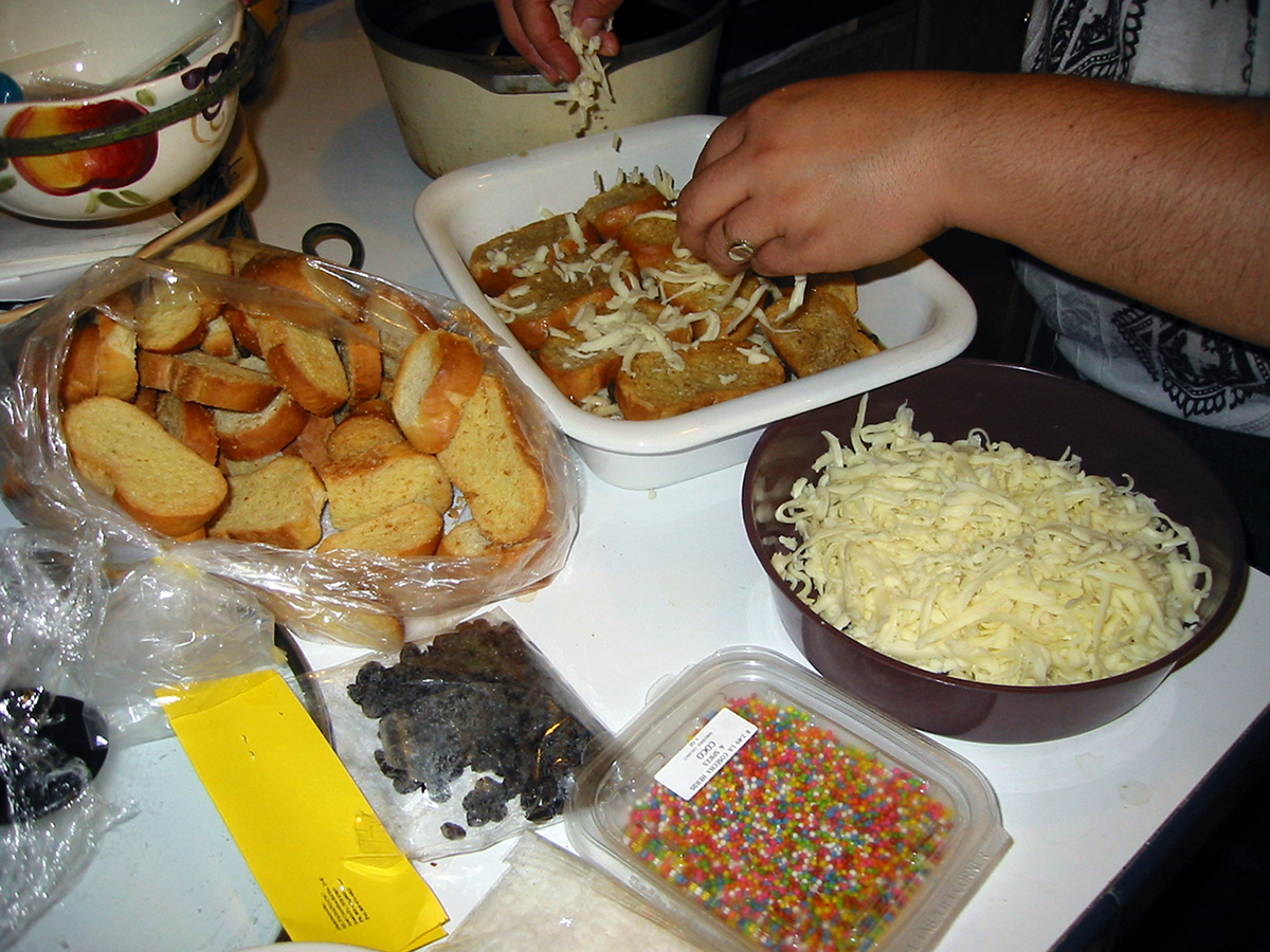 a hand sprinkling grated cheese over toasted bread