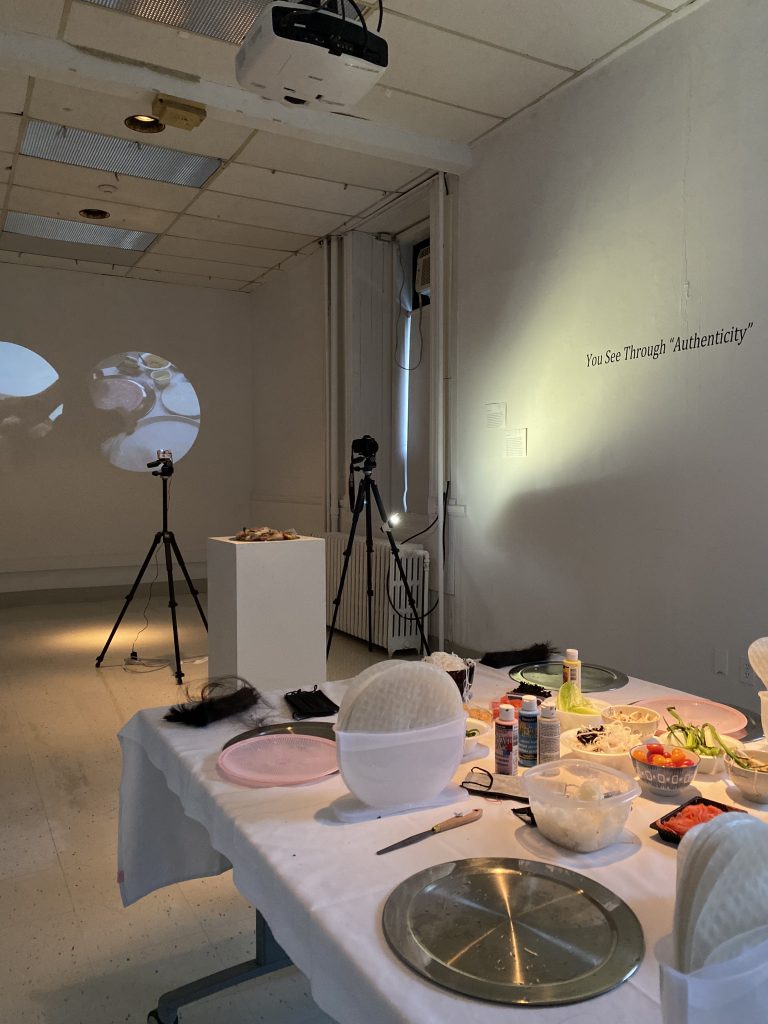 a gallery space with a table covered in food in the foreground