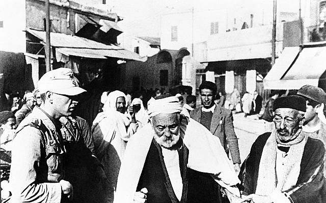 As a Nazi soldier looks at Tunisian men on the street on January 9, 1941.