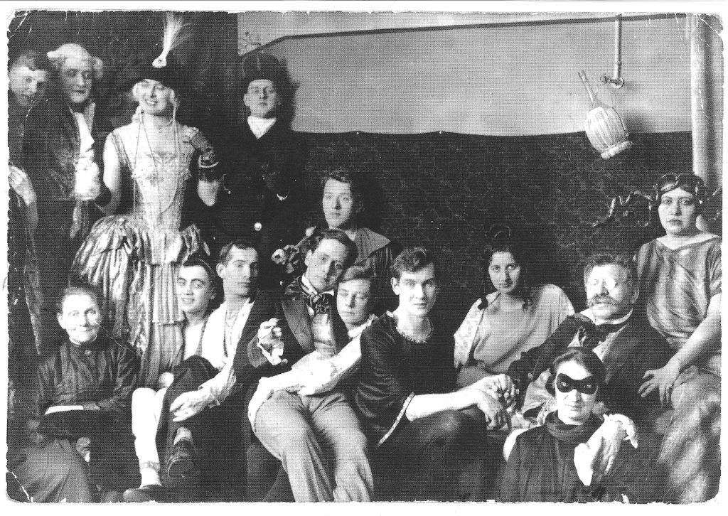 Une fête costumée à l'Institut de recherche sexuelle de Magnus Hirschfeld, à Berlin. Hirschfeld est représenté assis à droite, avec une grosse moustache et des lunettes ; ses doigts sont entrelacés avec ceux de son étudiant et amant, Karl Giese.