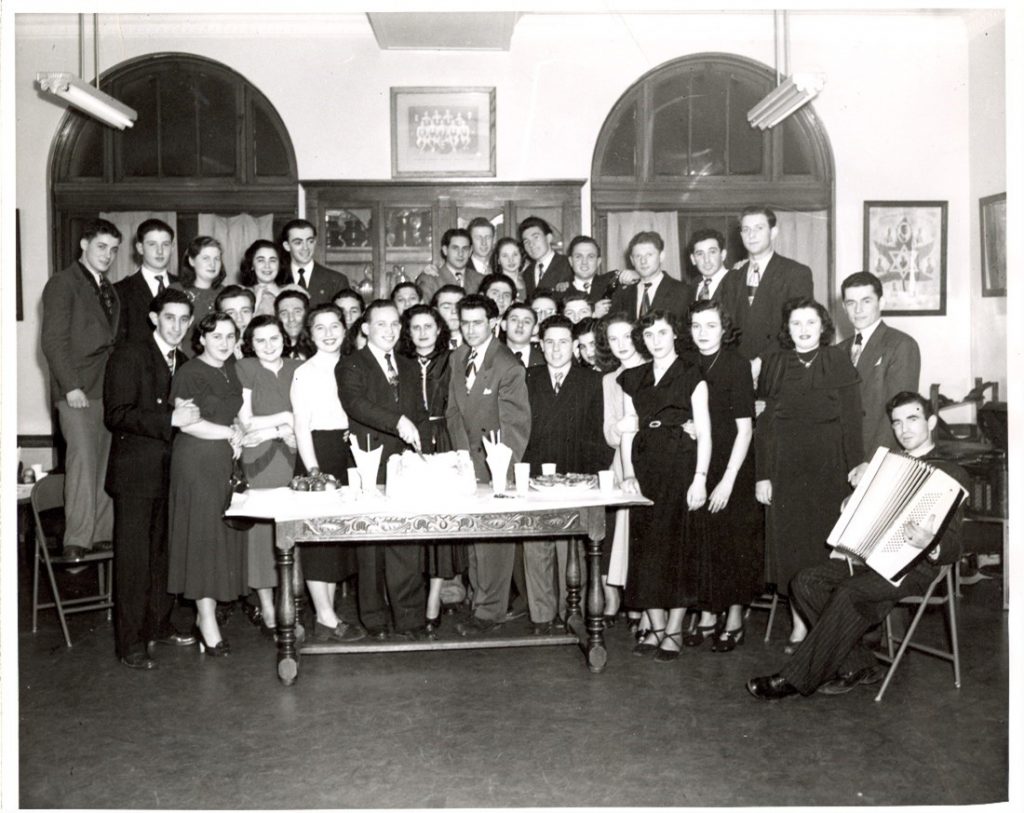 Gathering of the Hakoah New Canadians Club for newly arrived Holocaust Survivors at the YMHA in Montreal, Canada. Mitchell Seidenfeld, a Czechoslovakian Survivor, cuts the cake.